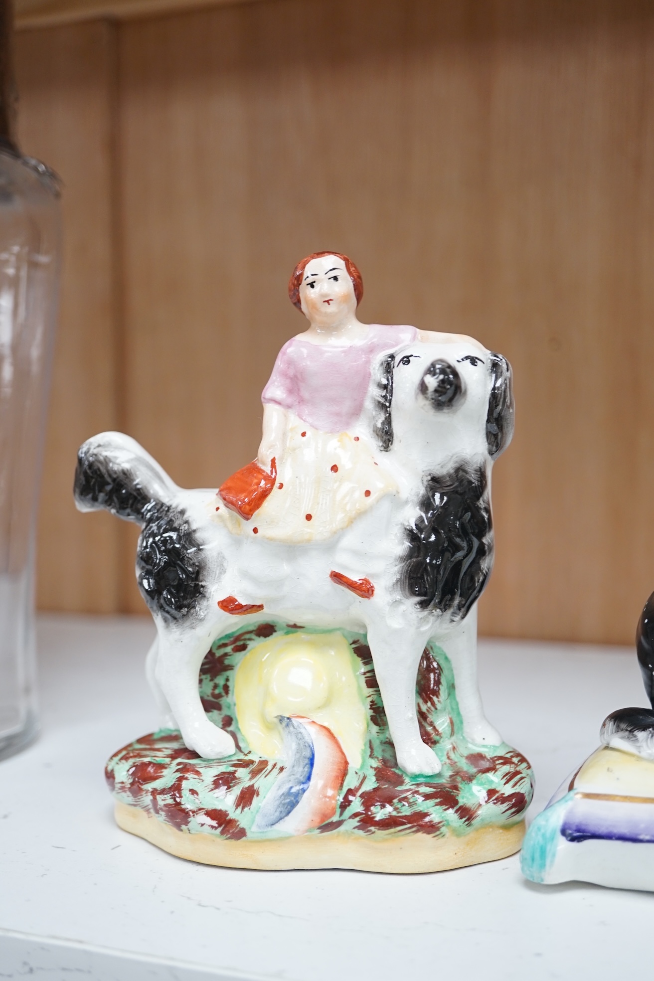 A pair of mid 19th century Staffordshire spaniels seated on cushions and a pair of similar groups of children riding spaniels (4), tallest 14cm. Condition - some minor flaking to paint, otherwise good